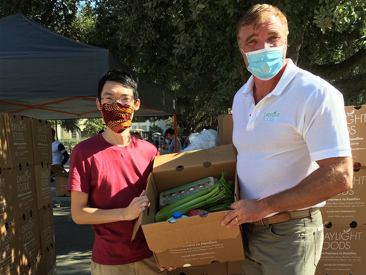 Two men hold box of food