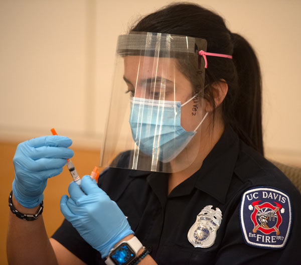 Student EMT (in uniform) prepares syringe.