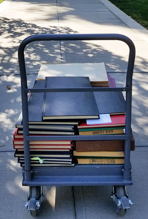 Bound copies of The Aggie on a cart headed to the library