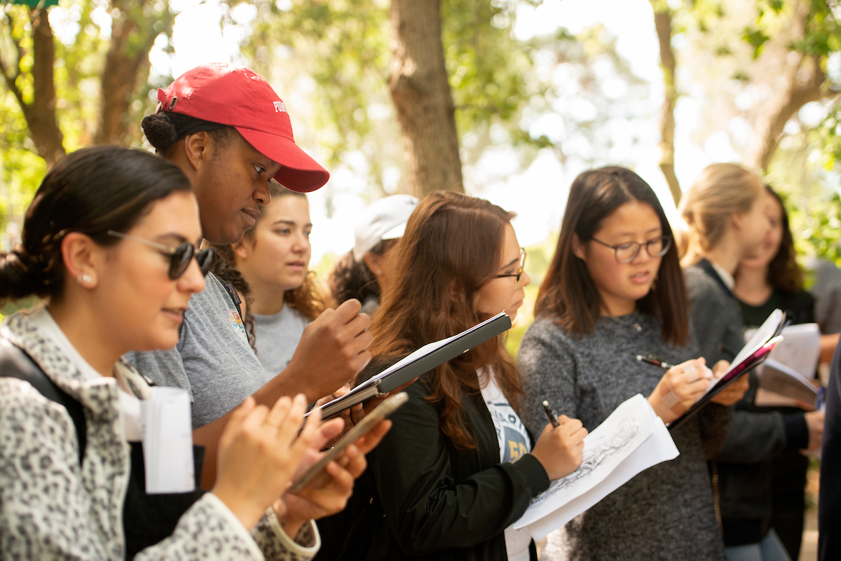 Students write in their notebooks outside at UC Davis. 