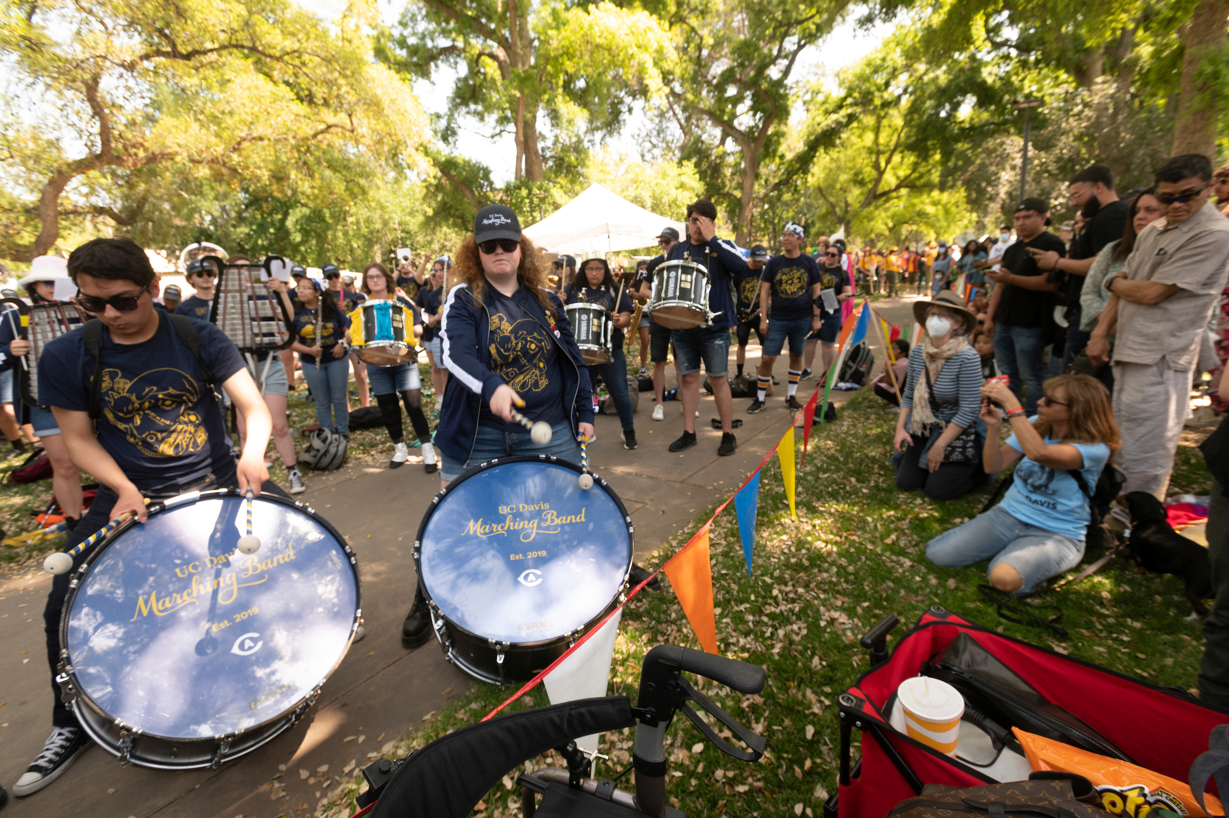 Band members on percussion instruments performing to outdoor audience