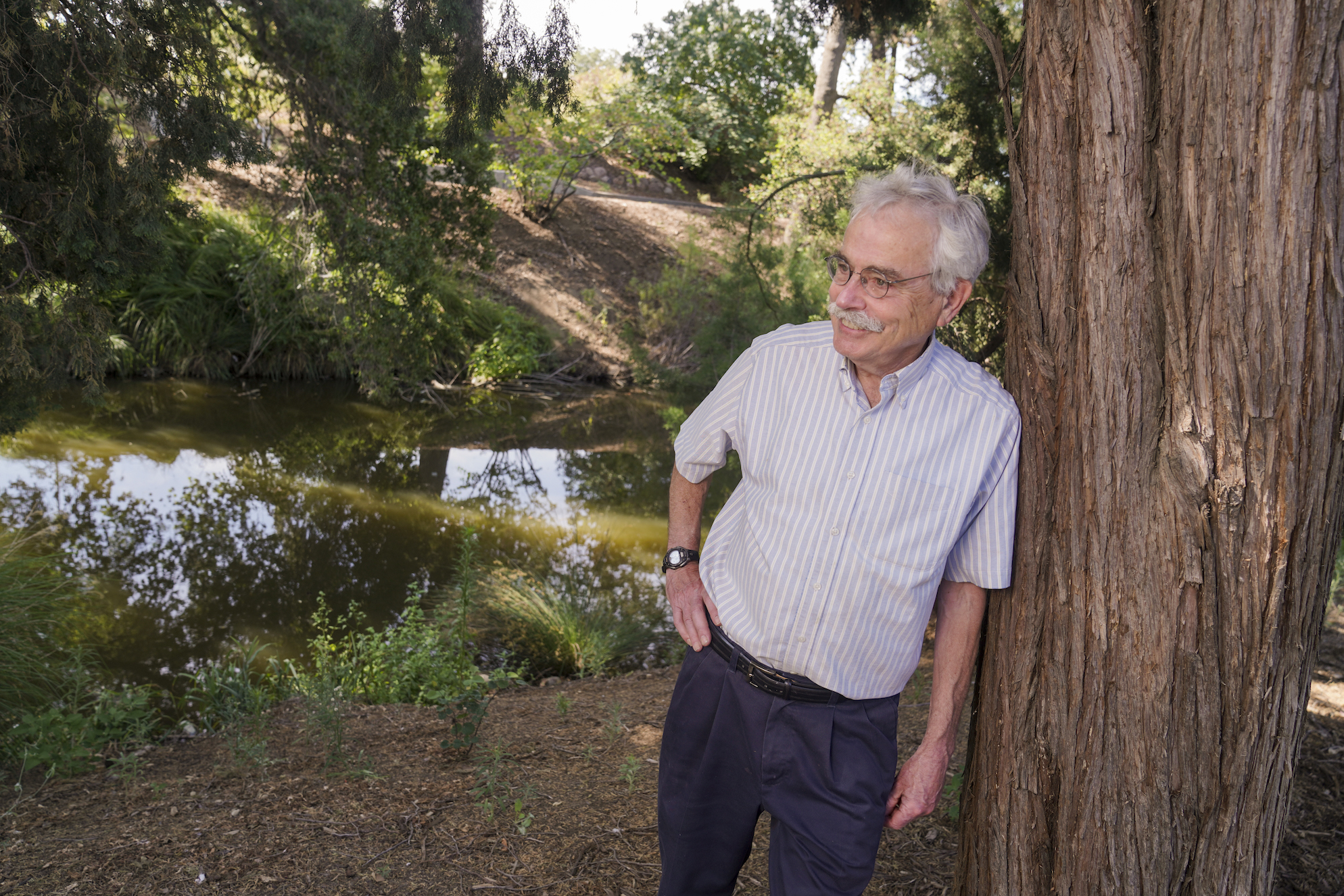 Peter Moyle leans against a redwood tree in the UC Davis Arboretum.