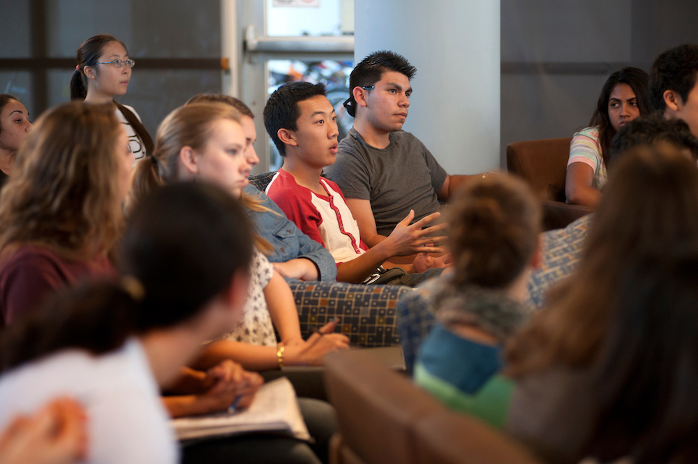 Students talk in a full lecture hall at UC Davis. 