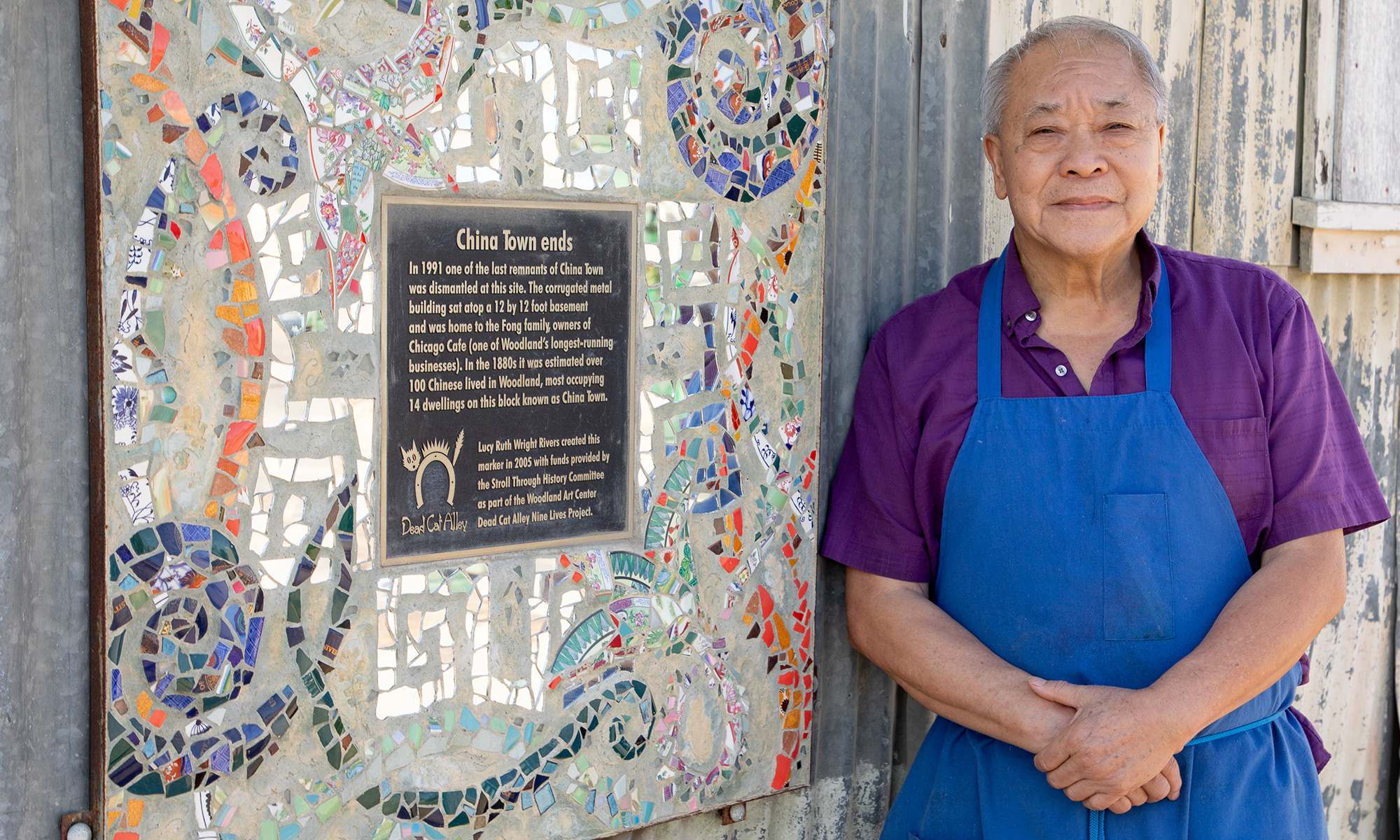 A man stands next to a historical plaque