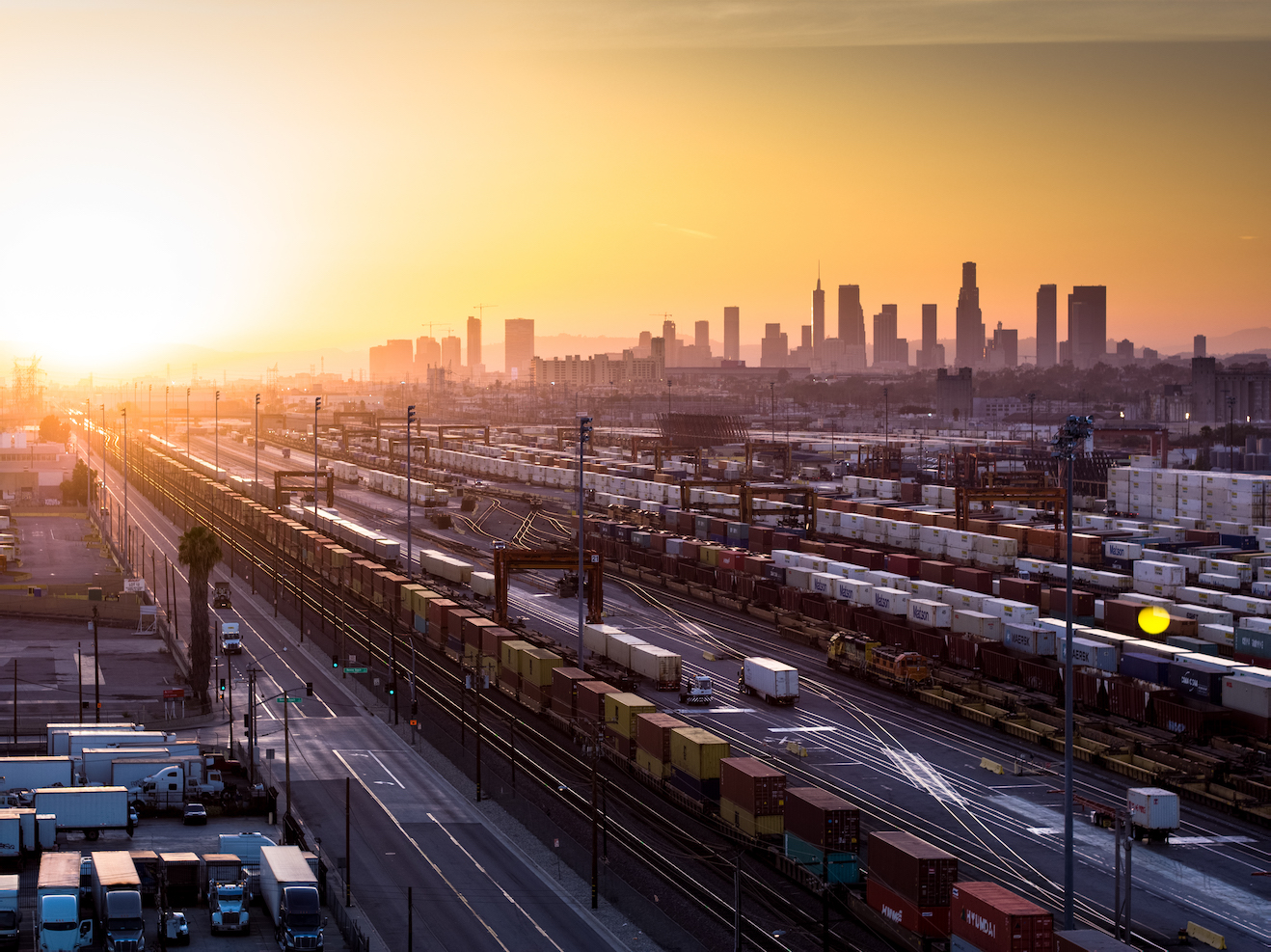 Aerial shot of freight yard with Los Angeles city skyline in backdrop