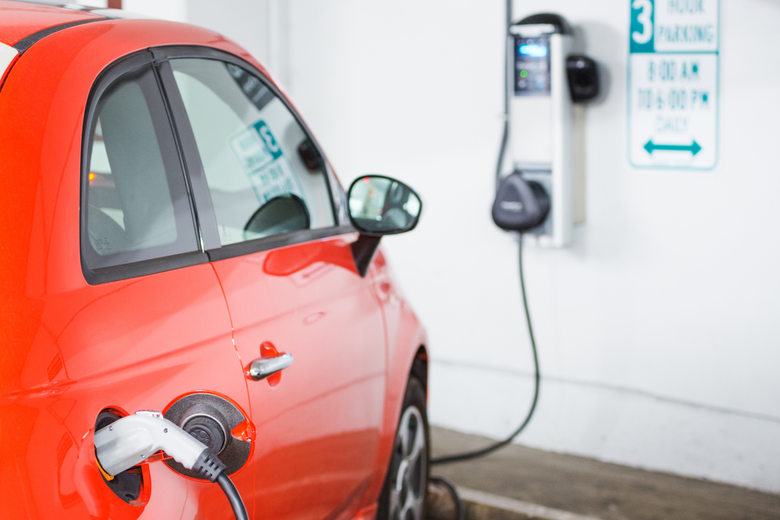 red electric vehicle charges in a parking lot