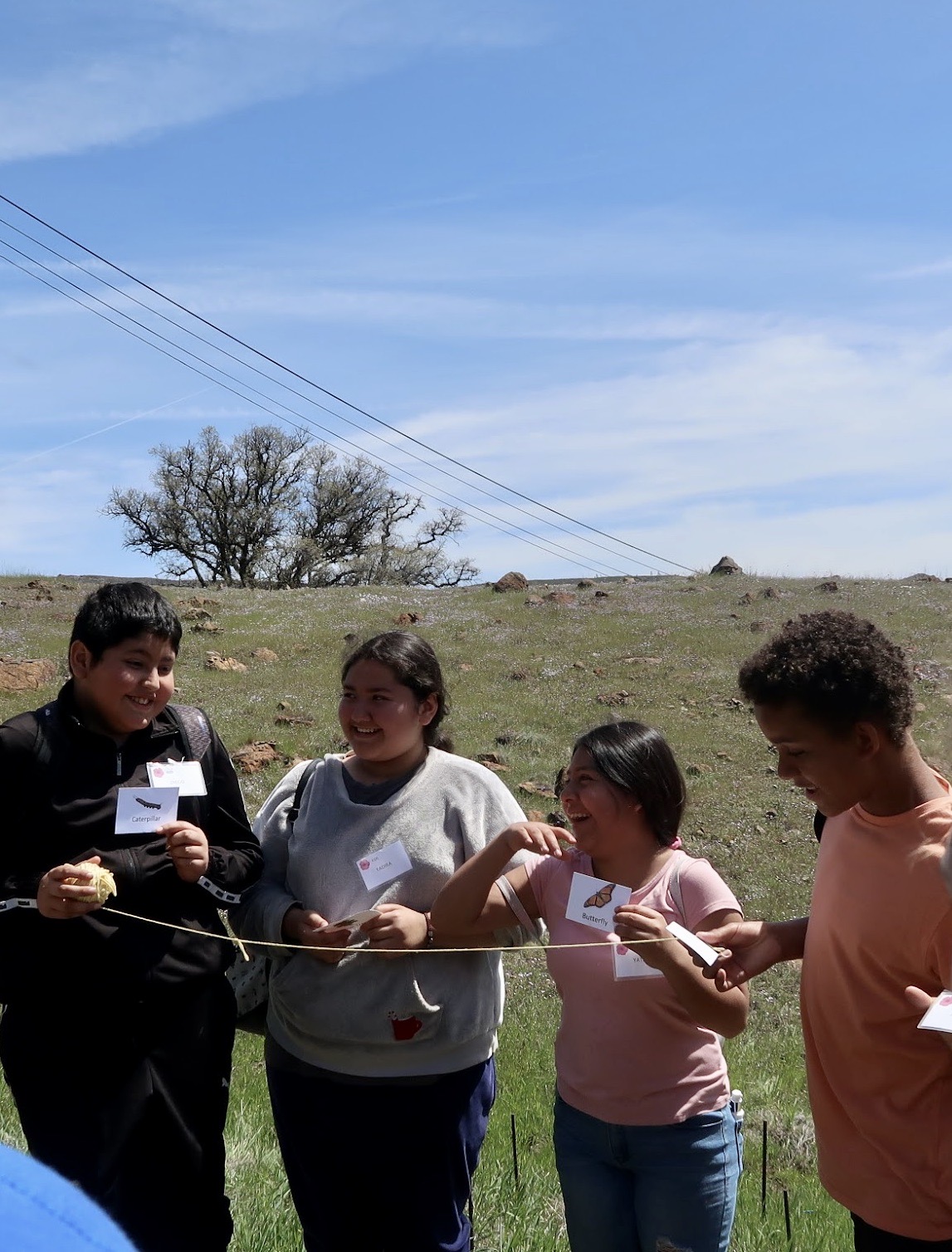 students laugh while passing a string, representing a food web