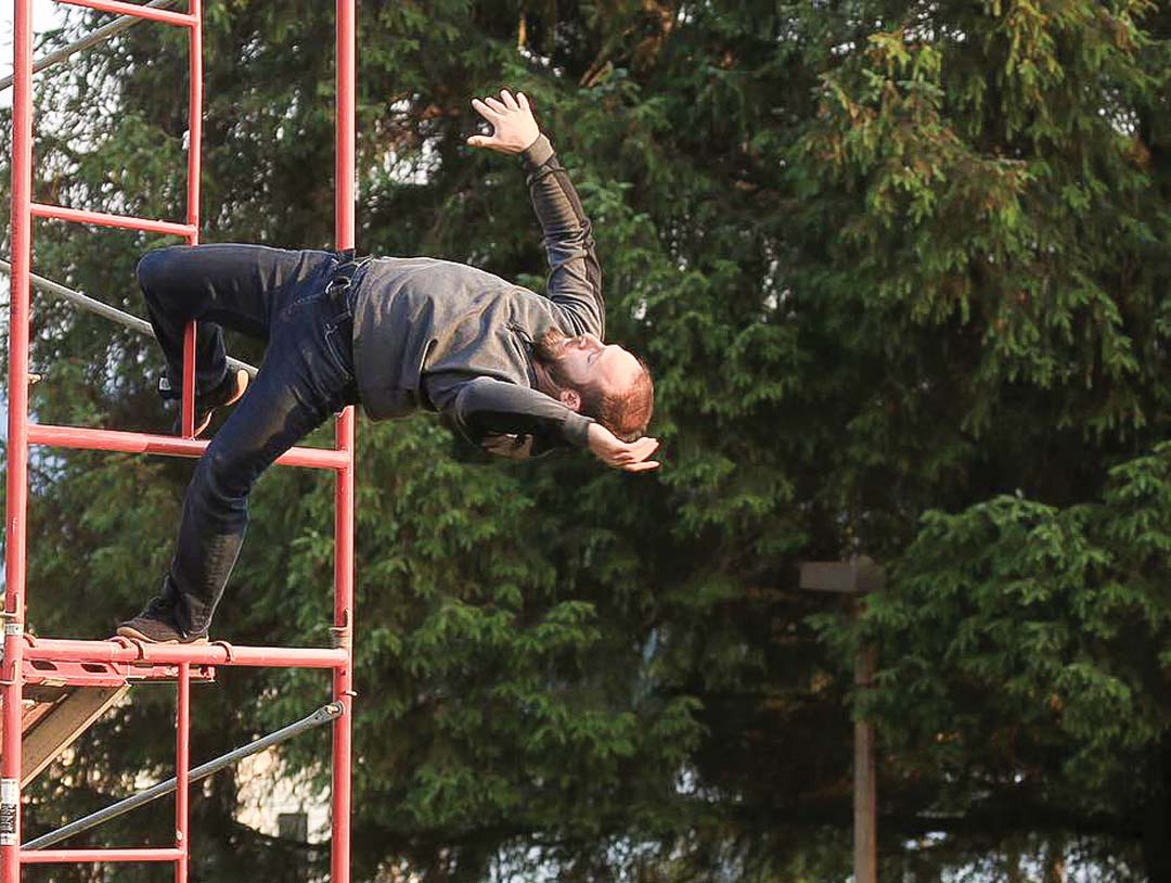 A man dangles backwards off the side of some scaffolding.