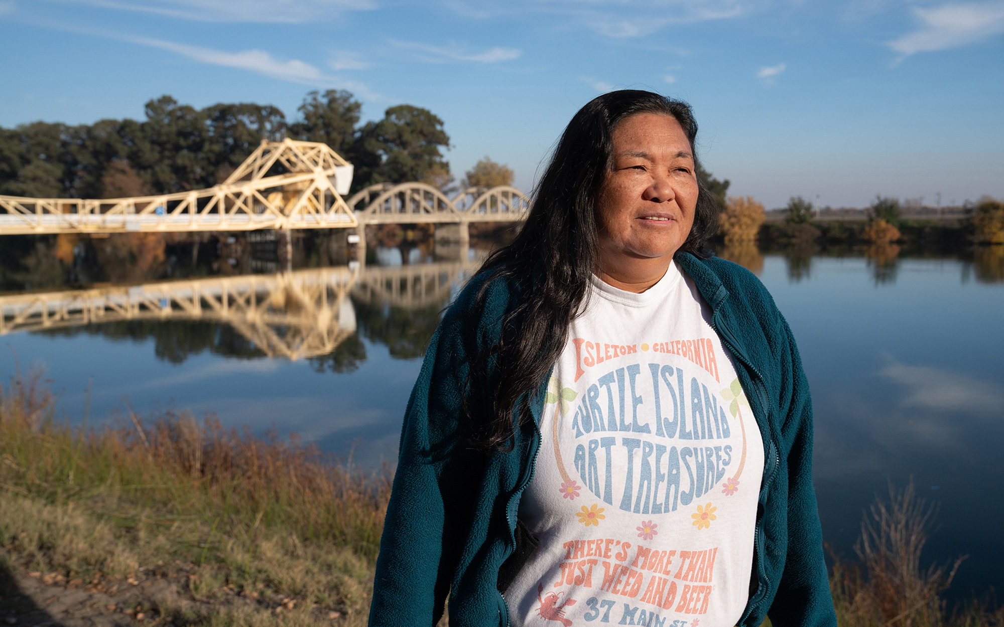 Woman stands by waterway and bridge