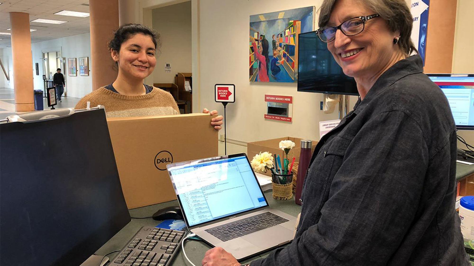 Women prepare loaner laptops for distribution.