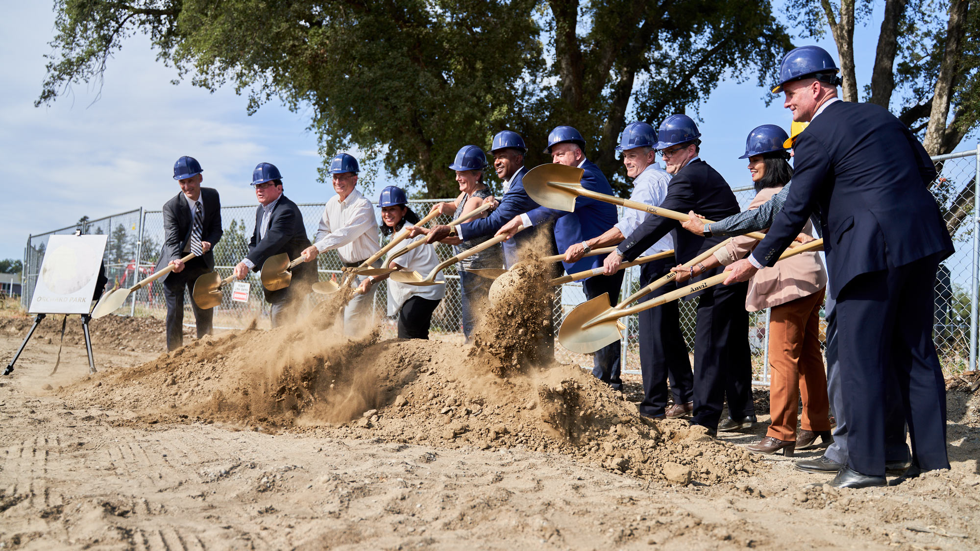 Dignitaries wield gold shovels at groundbreaking.