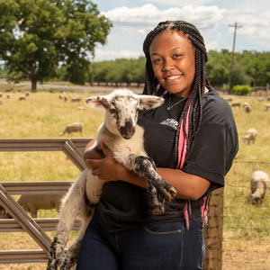 A female student holding a baby goat