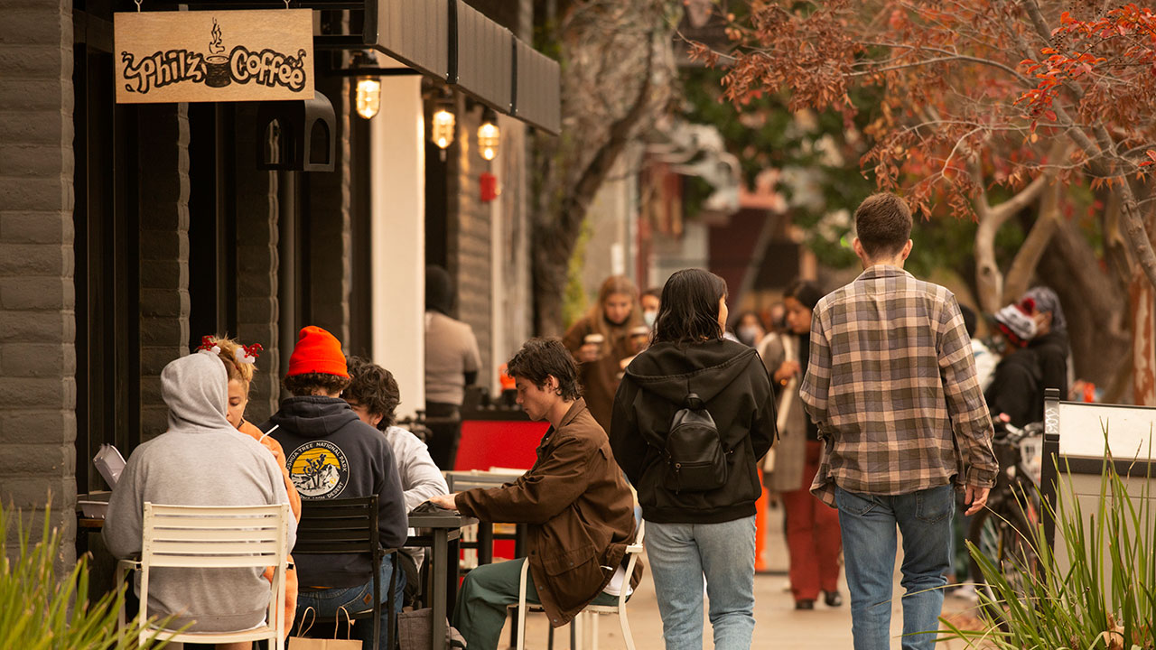 People walk and sit along a Downtown Davis street.