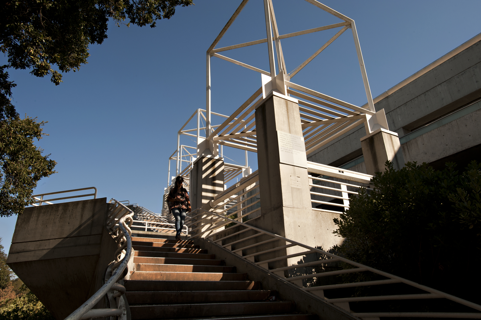 A woman walks down a staircase outside a parking structure.