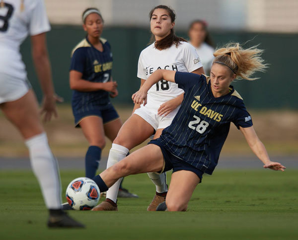 Aggie player on on knee, kicks ball.