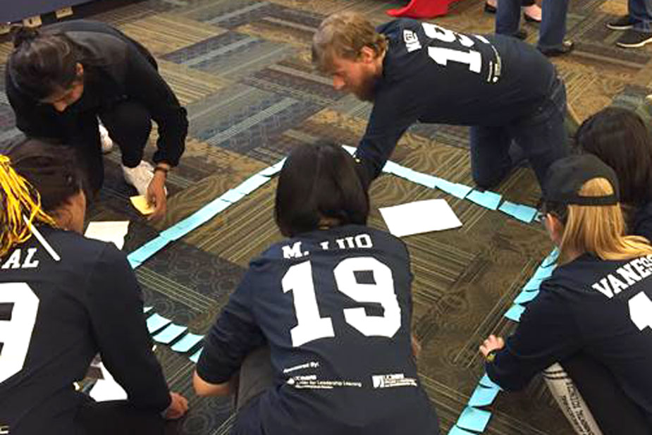 Students make a mural out of Post-it notes, on the floor.