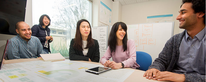 Professor, second from right, talking with her graduate students while seated at a table