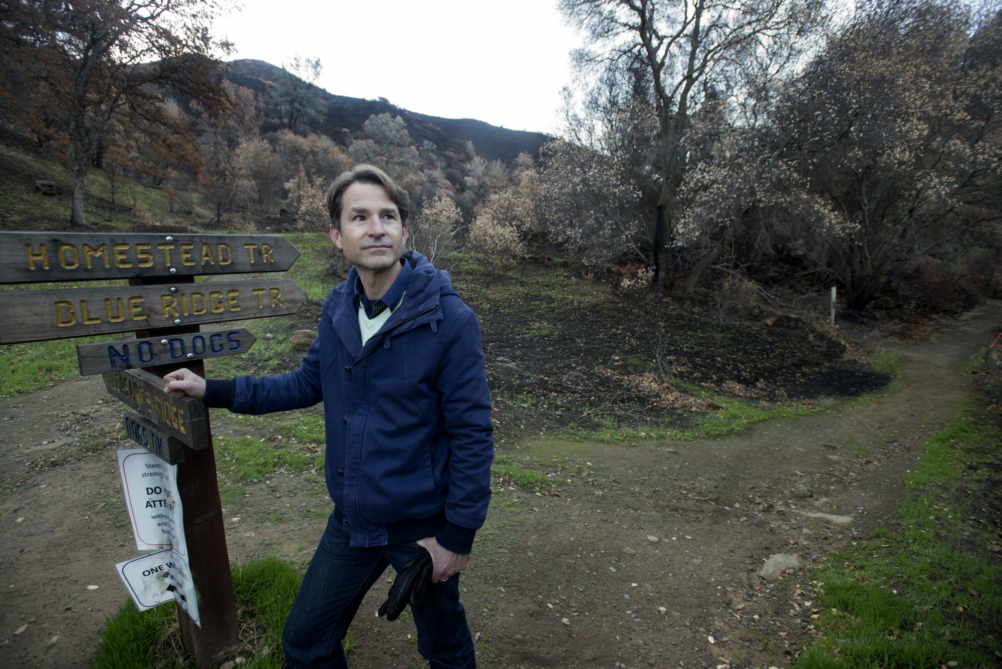 Man stands beside sign in natural reserve