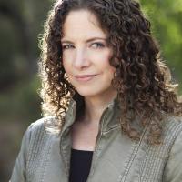 A portrait of Karima Bennoune standing outside with some green bushes in the background.