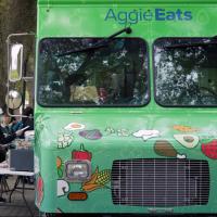 students waiting at a green food truck for food