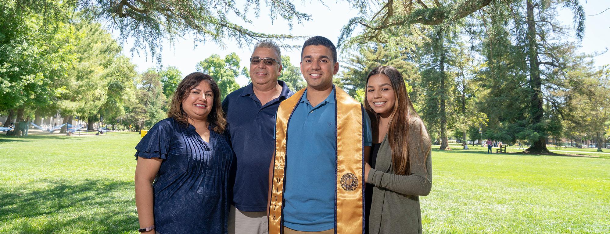 Parents pose with their UC Davis graduate son on the quad 