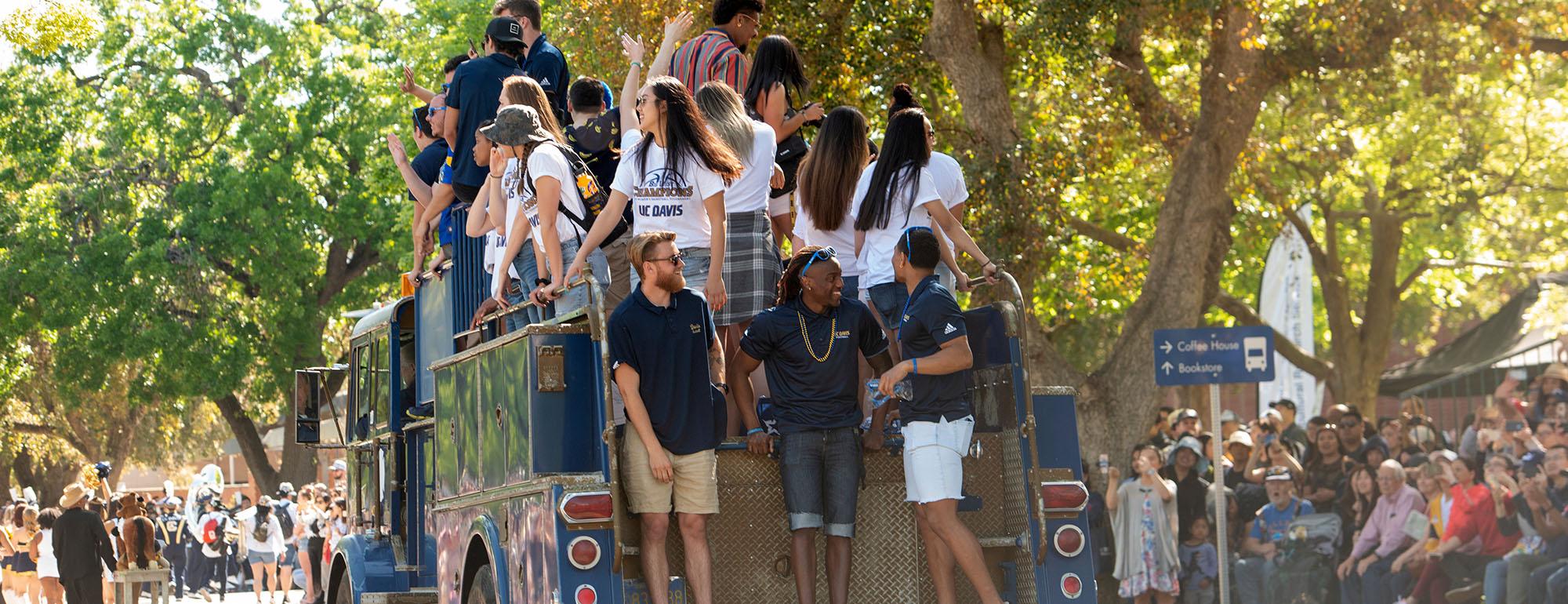 picnic day parade onlookers watch a firetruck full of students wave to the crowd