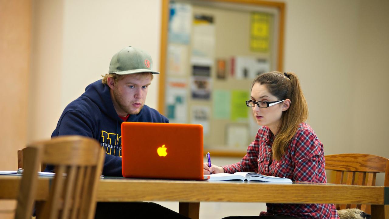 Two students work in front of a laptop at UC Davis.