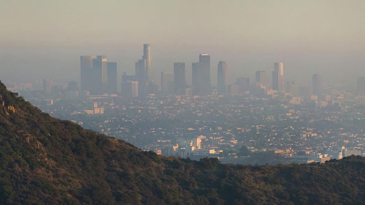 Photo of a city downtown, seen from a distance, shrouded in smog.