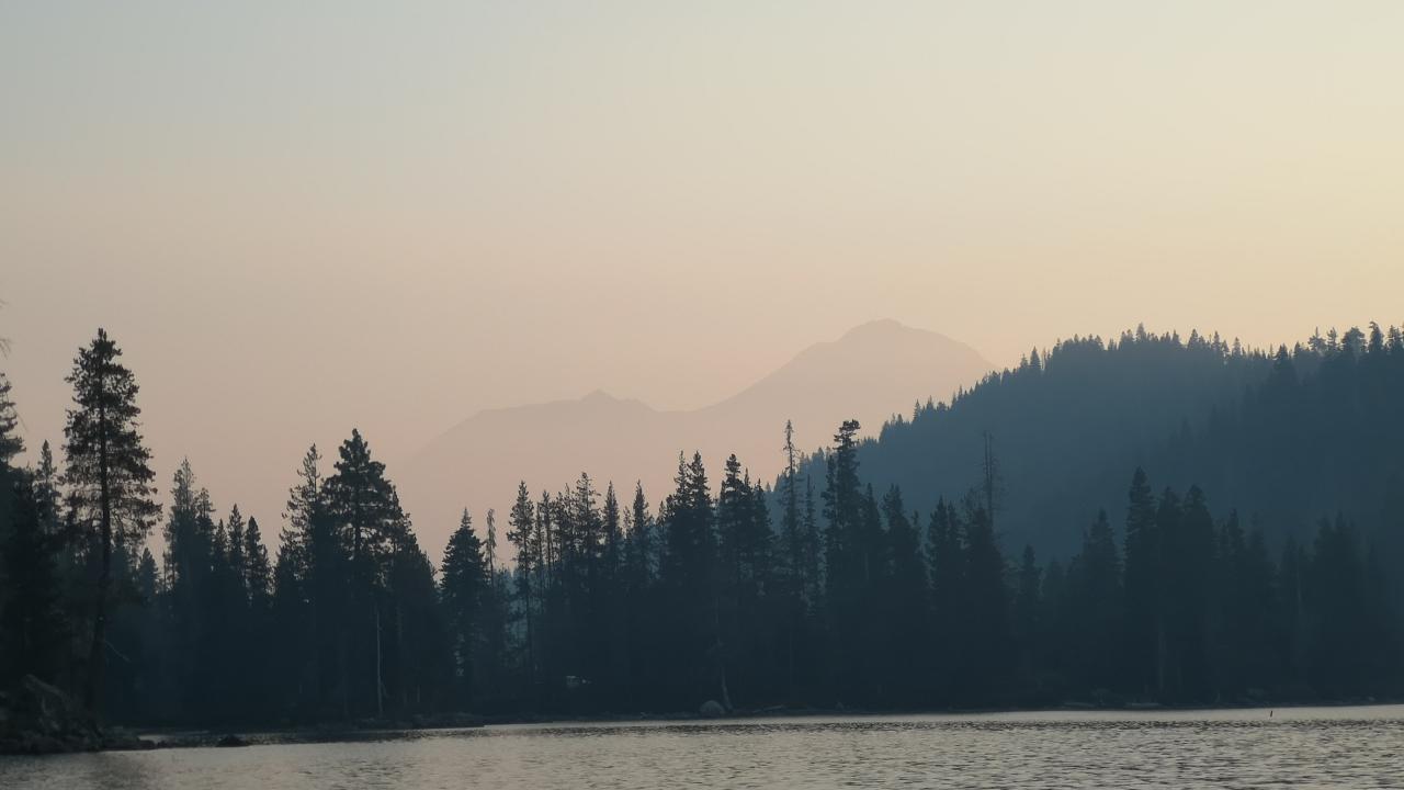 Smoke above Castle Lake with silhouette of mountains and trees 