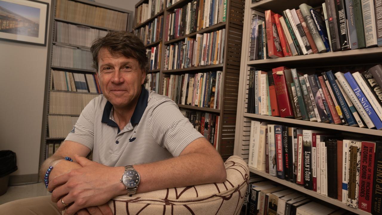 Man sitting on chair with books in background