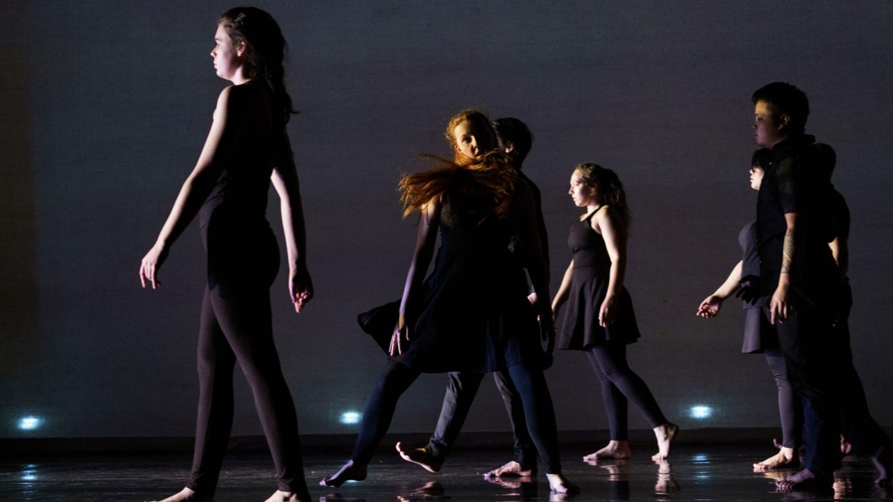 Performers in dark stage dance performance