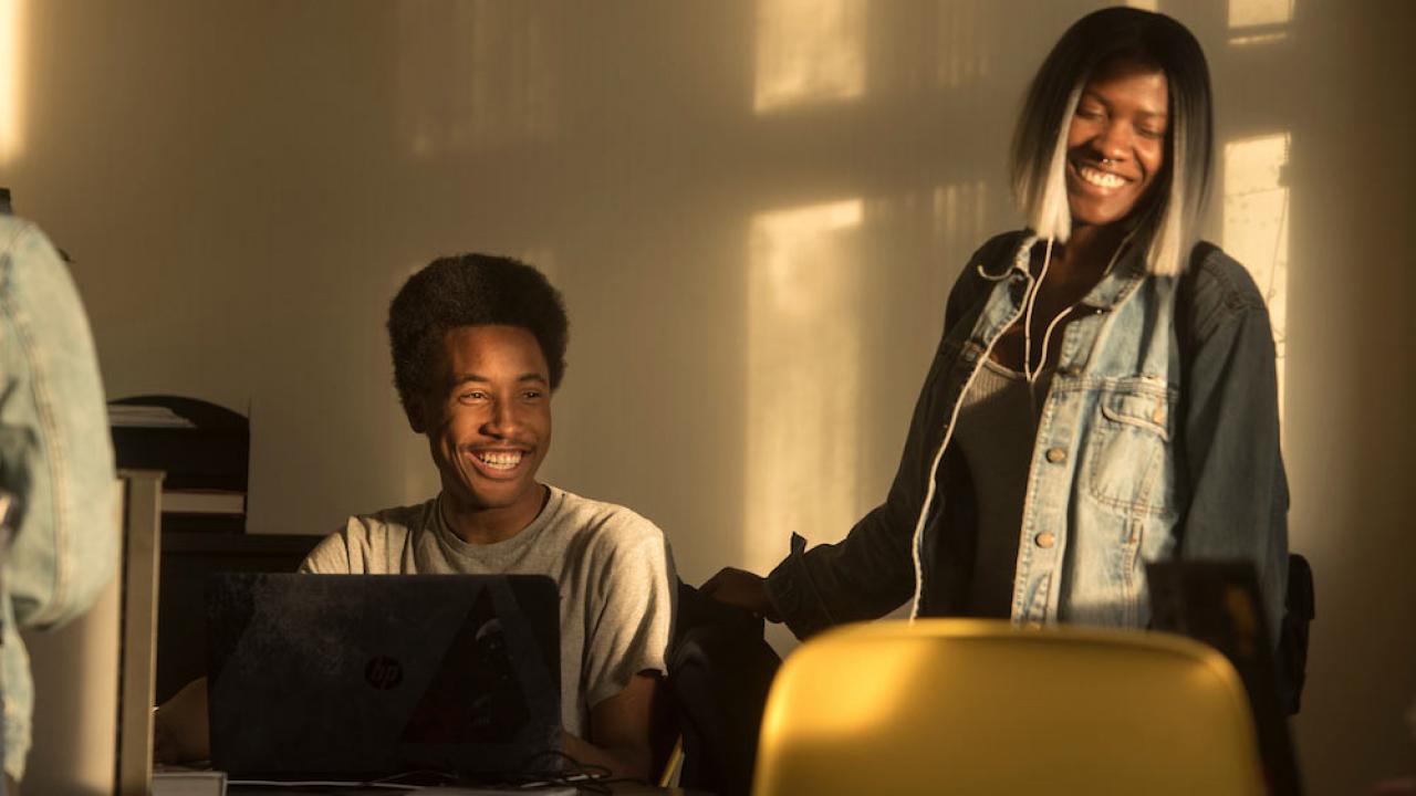 Two students laugh while collaborating on a project