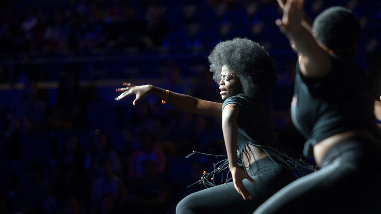 A female students dances on stage in front of a large crowd