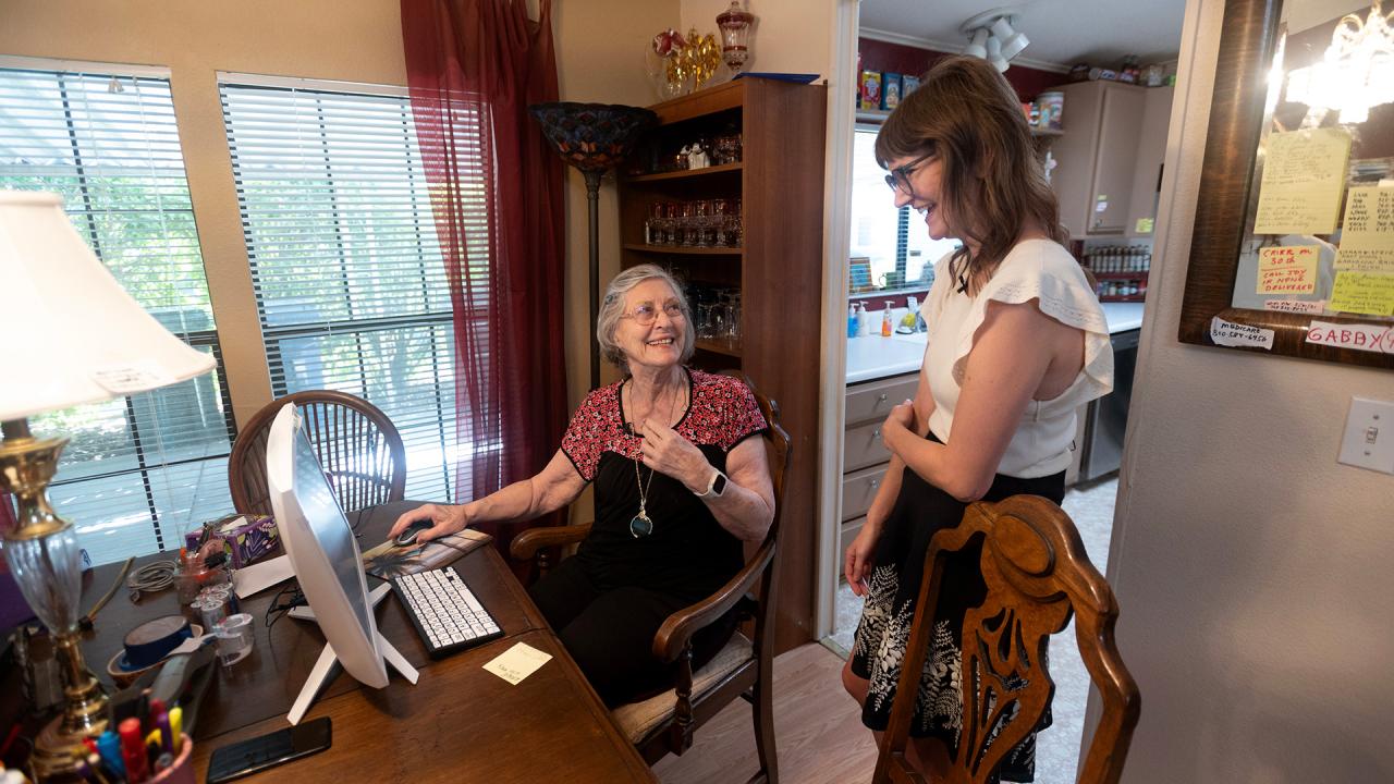 Researcher talks with older patient in her dining room