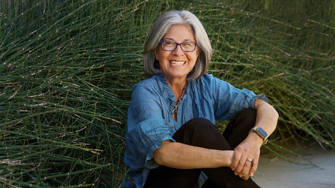 Woman sits in front of plants.