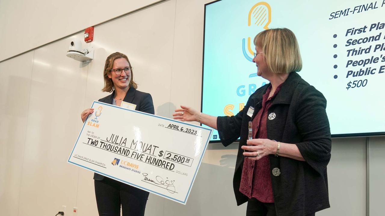 Student stands with giant check made out to Julia Mouat