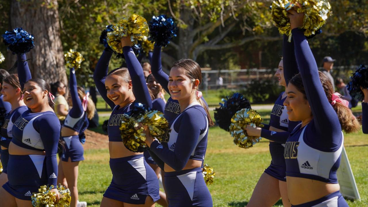 Members of the UC Davis Cheer Team raises pompoms at 2021 Homecoming Pep Rally