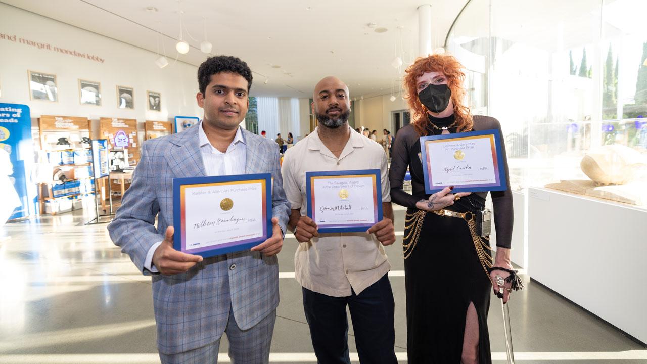 Three award winners stand with museum in background at a ceremony June 6, 2024