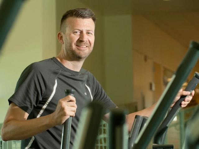 A staff member riding an eliptical exercise machine