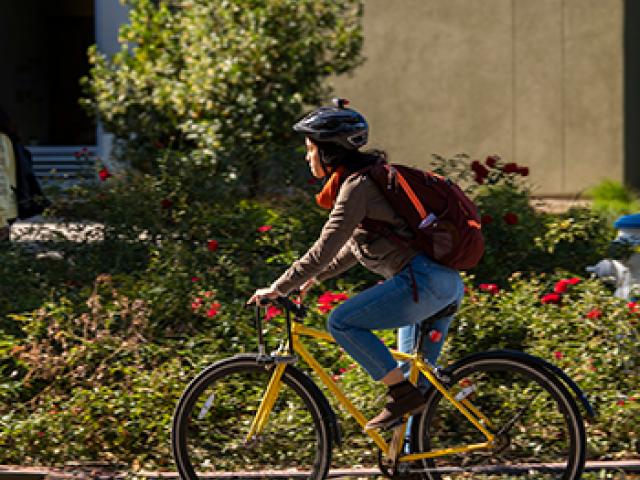 student rides a bicycle while wearing a helmet