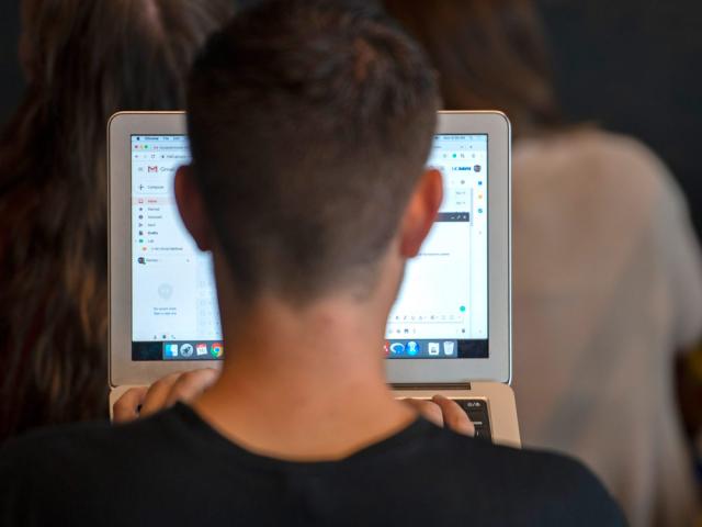 back of students head as they're looking at a laptop