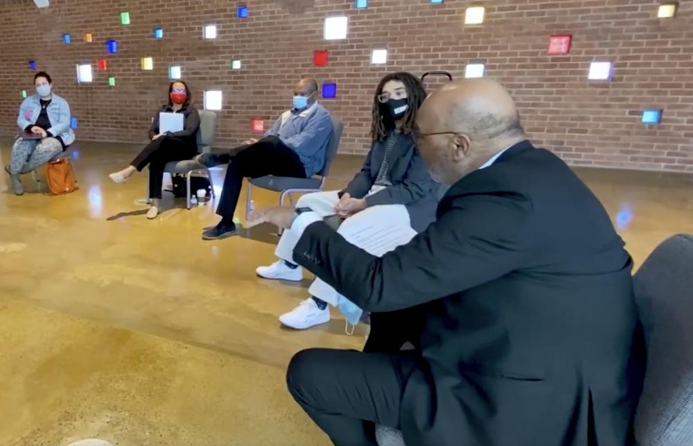 A small group sits in a spaced-out ring in a church