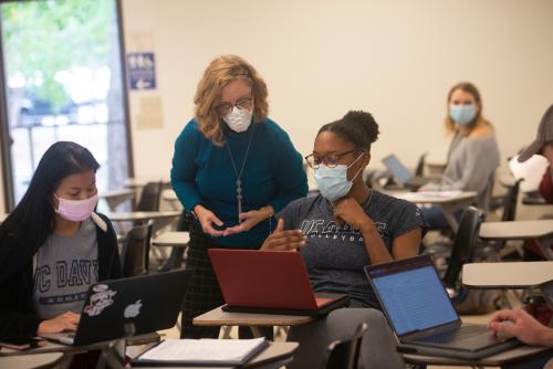 Professor Standing and Mentoring Students In a Classroon