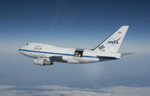 Boeing 747 in flight with a large rectangular door open towards the rear of the airplane. 