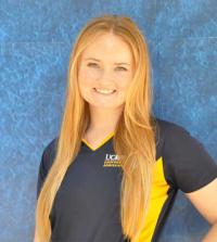 A portrait of Olivia Westall, who is posing and smiling against a bright blue background.