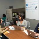 Three women sit around a table having a meeting.