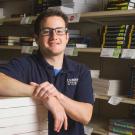 Male student leaning on a stack of books