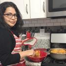 Assistant Professor Lilian Cruz-Orengo cooking looks forward to sharing traditional Puerto Rican flavors with e