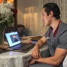 Medical student Dagoberto Pi&ntilde;a speaks to a patient on a laptop.