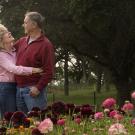 A couple embraces amid flowers and greenery